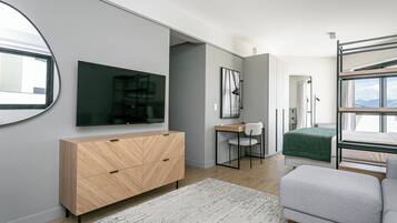Un dormitorio moderno con literas, un escritorio, una silla, un televisor y un armario.