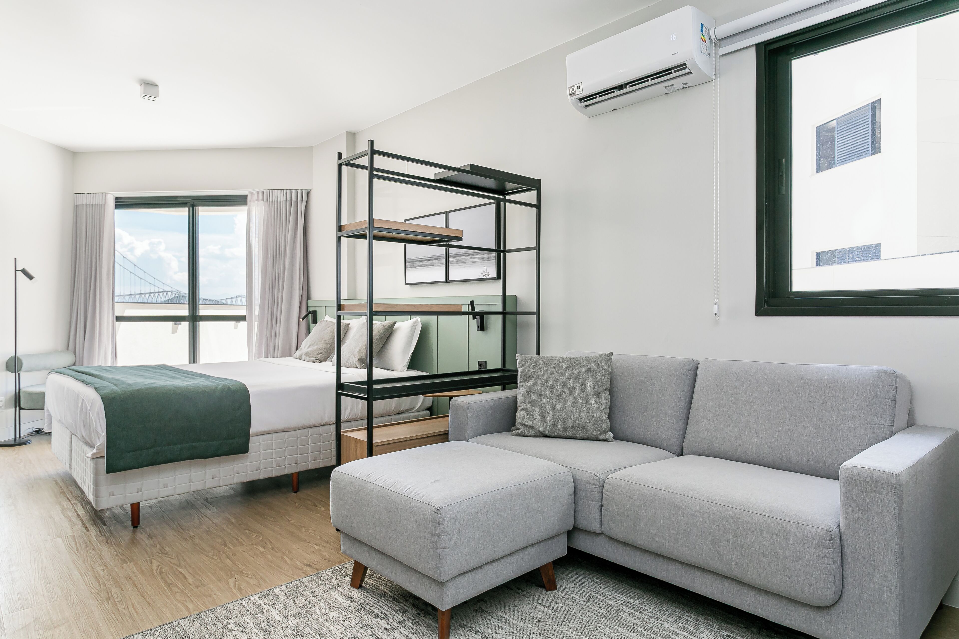 Et moderne hotelværelse med seng, sofa, køjeseng og et stort vindue med gardiner.