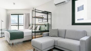 Et moderne hotelværelse med seng, sofa, køjeseng og et stort vindue med gardiner.