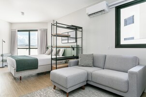 Et moderne hotelværelse med seng, sofa, køjeseng og et stort vindue med gardiner.