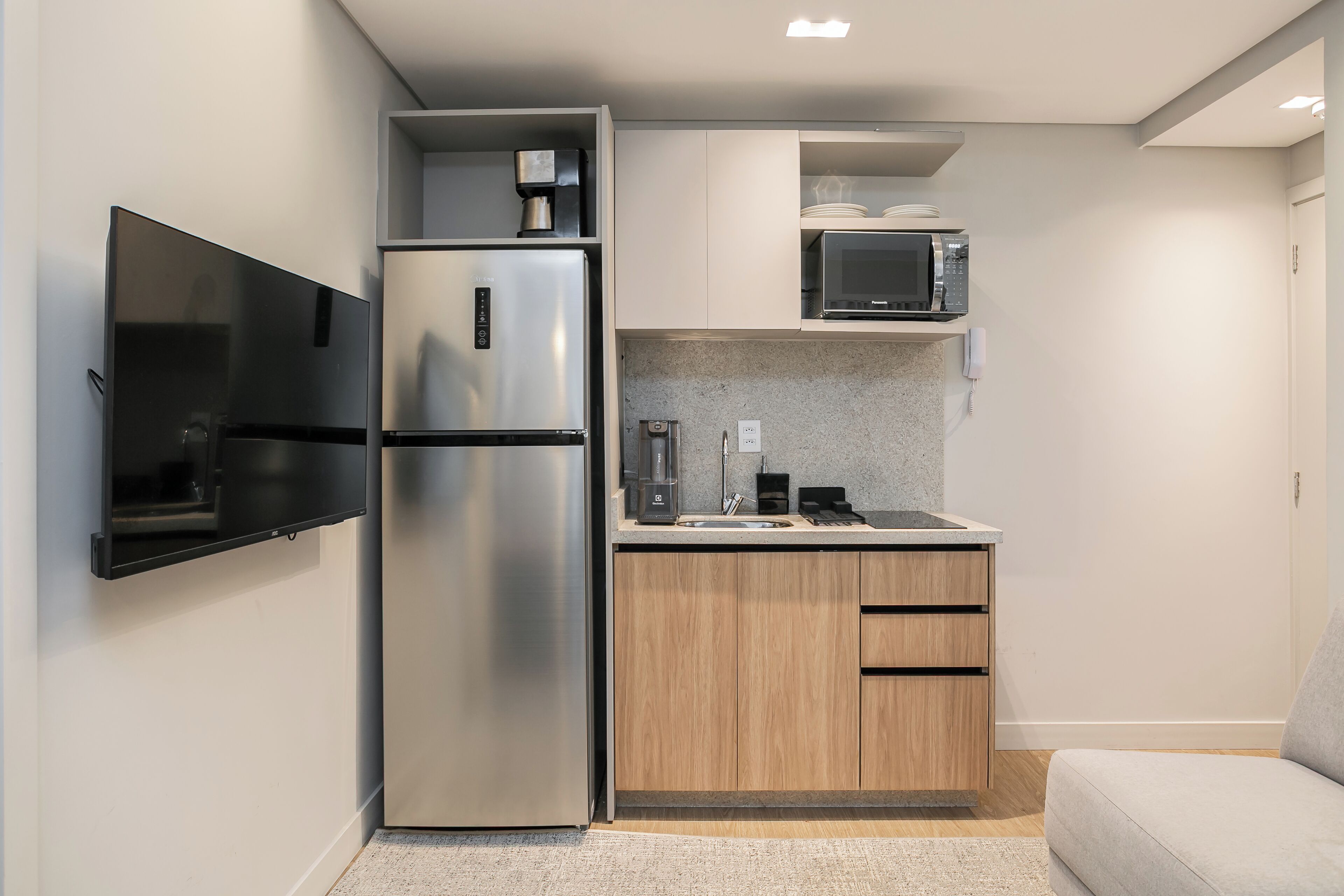 Una cocina compacta equipada con refrigerador, microondas y cafetera.