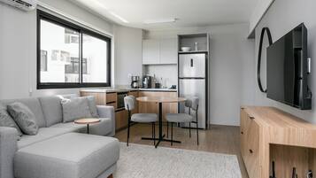 Una cocina moderna con un sofá gris, una mesa redonda y un televisor montado en la pared.