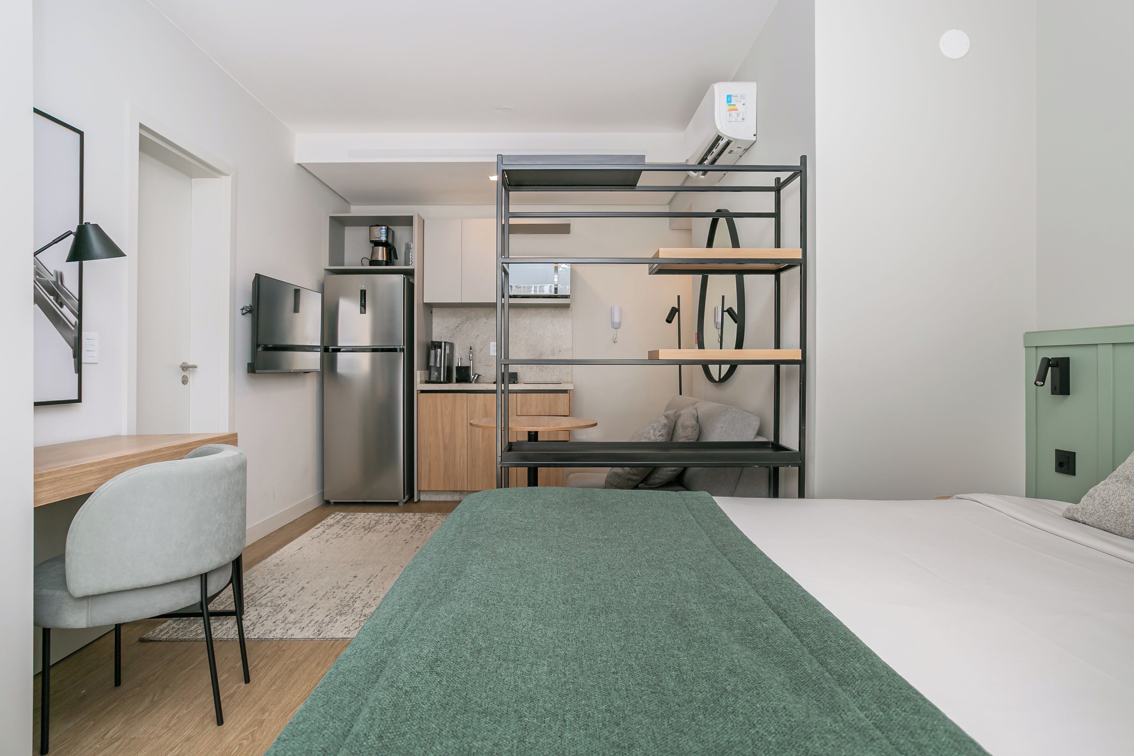 A compact room with a bunk bed, kitchenette, and a desk area.