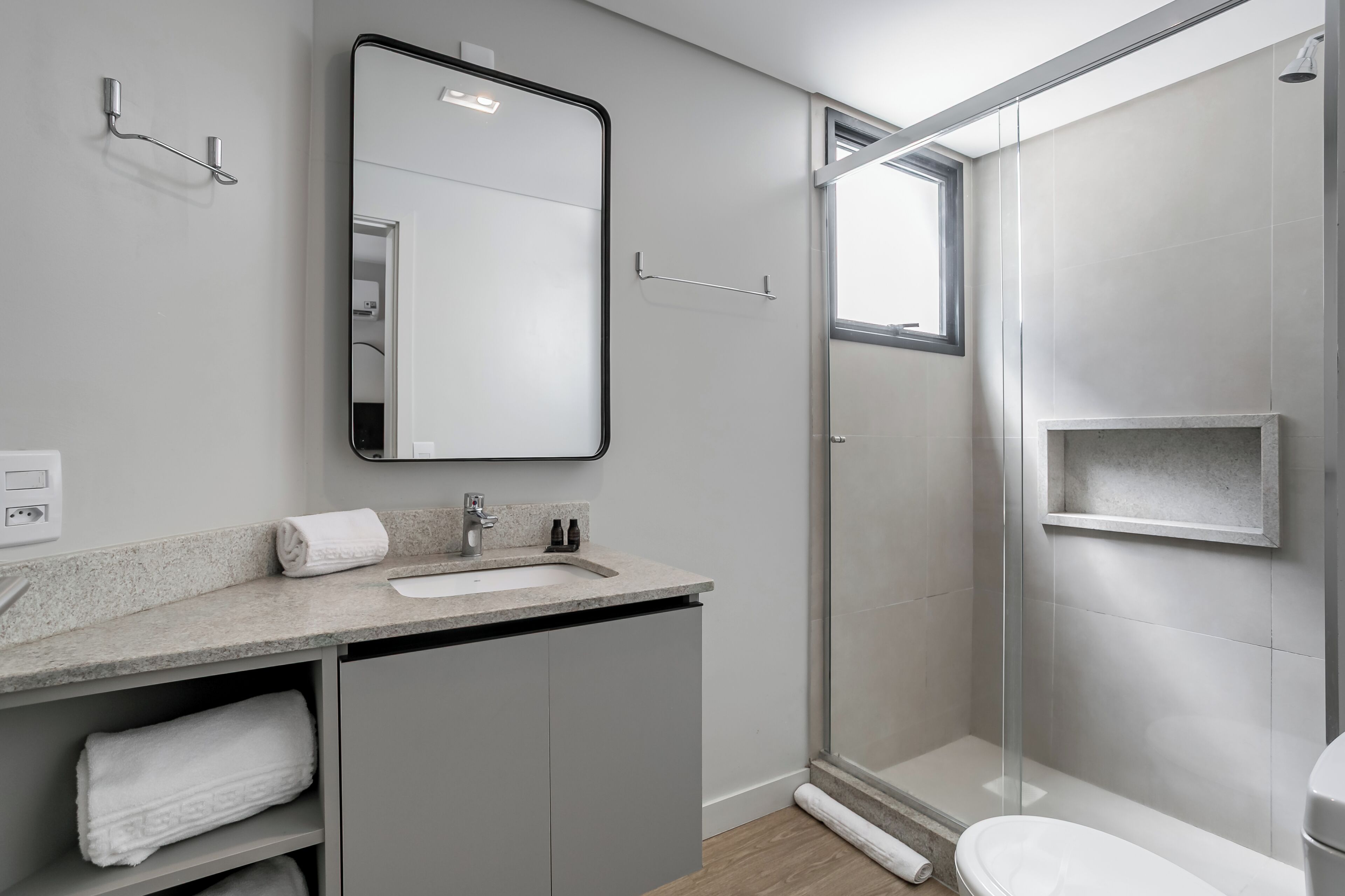 Ein modernes Badezimmer mit einer Duschkabine, einem Waschbecken mit Spiegel darüber und einer Toilette.