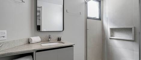 Ein modernes Badezimmer mit einer Duschkabine, einem Waschbecken mit Spiegel darüber und einer Toilette.