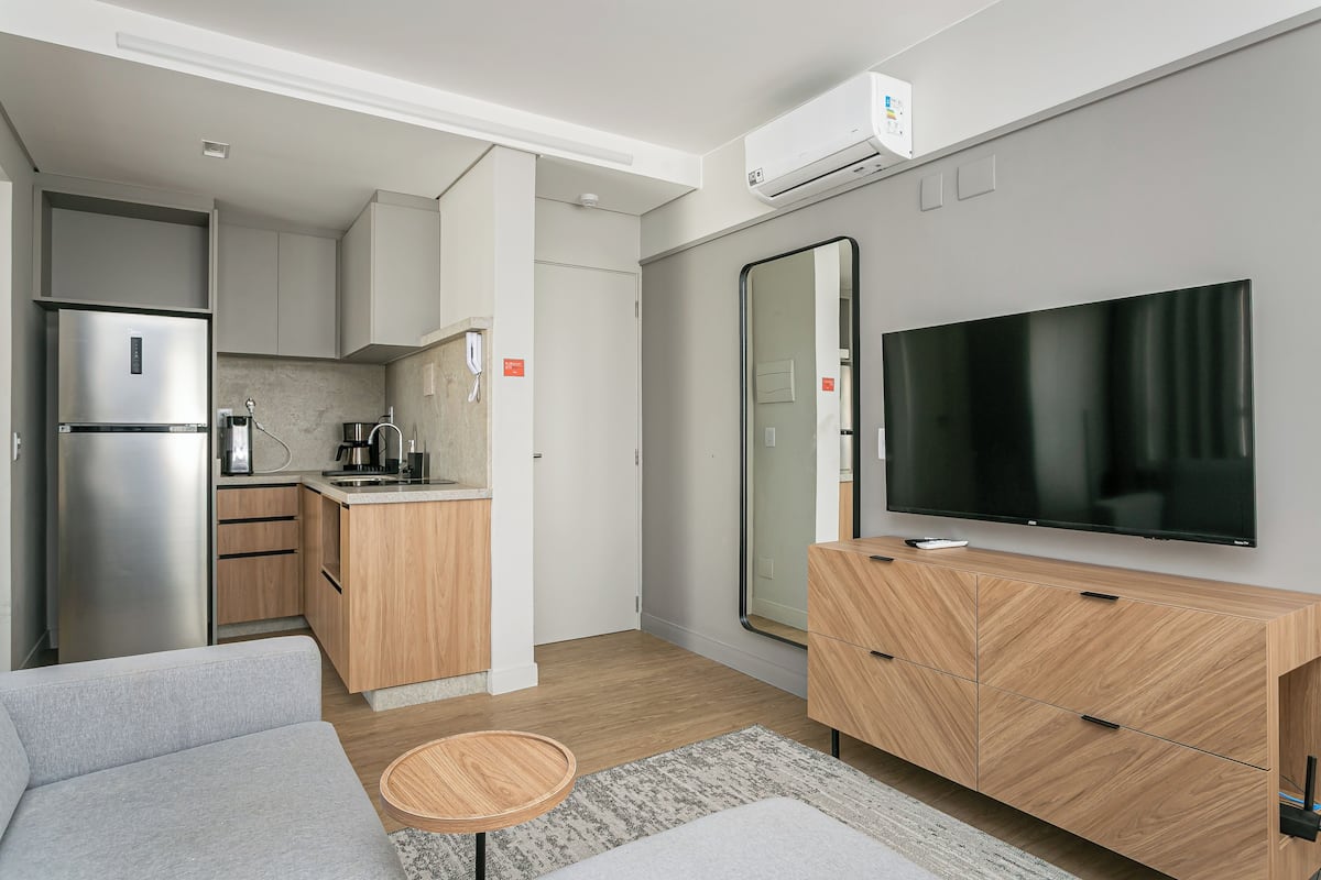 A compact living space with a kitchenette, a flat-screen TV, and a sofa.