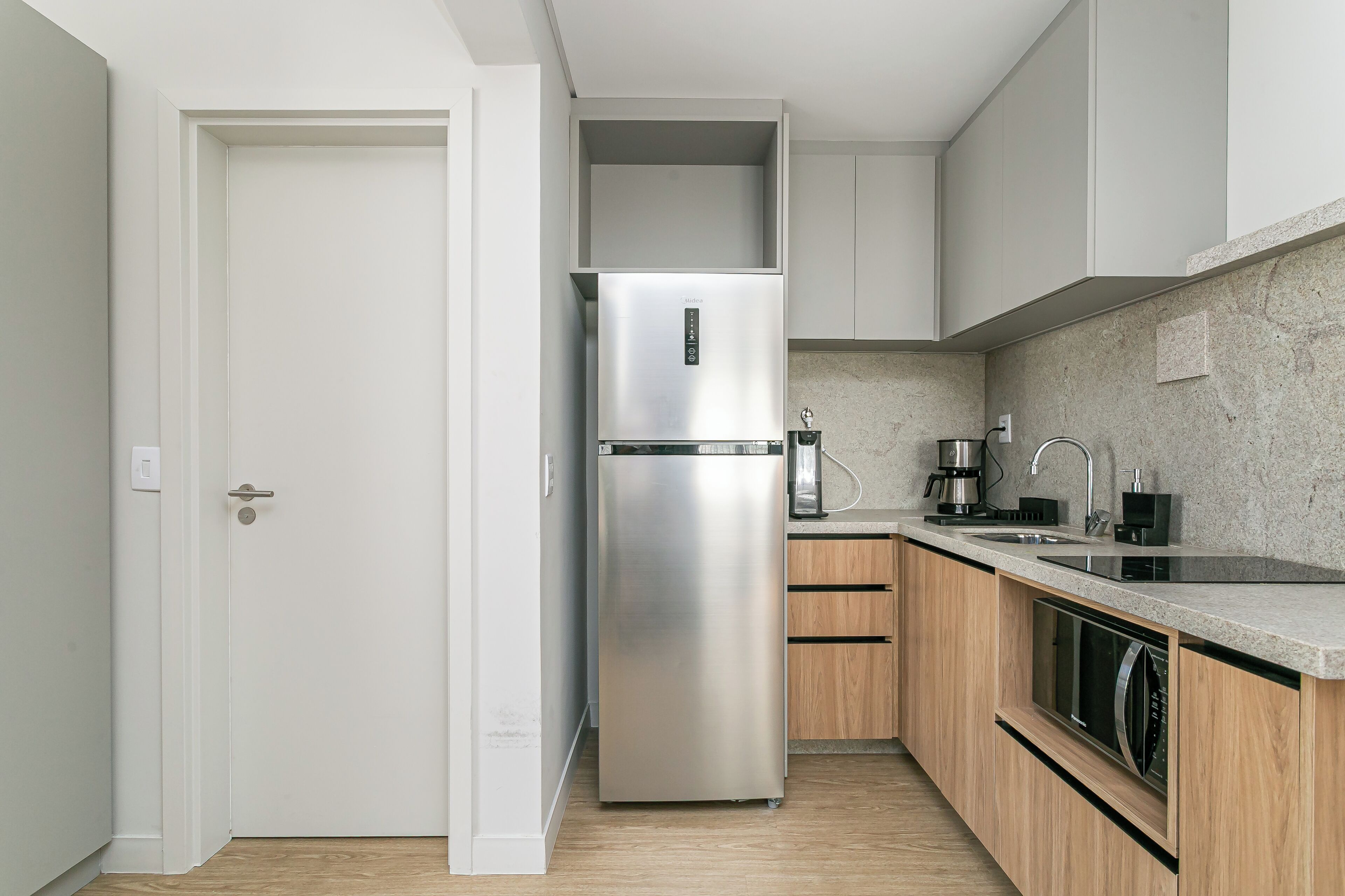 A modern kitchen with a stainless steel refrigerator, wooden cabinets, a built-in dishwasher, and a granite countertop.