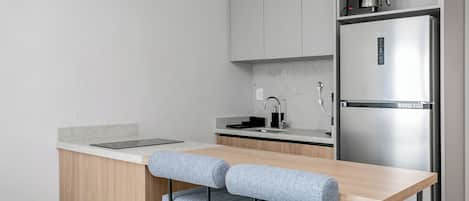 Una cocina moderna con encimera de madera, refrigerador de acero inoxidable y cafetera.