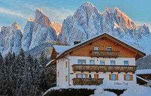 A mountain lodge with a wooden facade, balconies, and a view of snow-covered peaks. - Apartment 'Bergblick' with Mountain View, Shared Terrace and Wi-Fi (St. Maddalena)