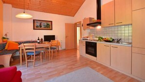 Une cuisine moderne avec des meubles en bois, un coin repas comprenant une table et des chaises, et un tableau accroché au mur.