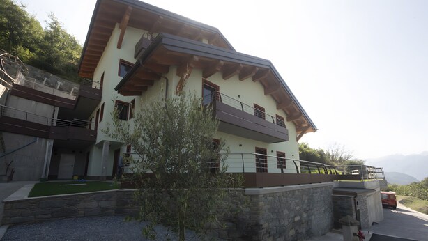 A two-story building with a balcony, a stone wall, and a small tree in the foreground. - Suly Apartments 5 - cir0086 (Cillian)