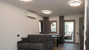 A modern living room with a grey sofa, a dining table with chairs, and a kitchen area. - Suly Apartments 5 - cir0086 (Cillian)