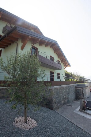 Un bâtiment doté d’un toit en pente, de murs en pierre et d’un petit arbre au premier plan.