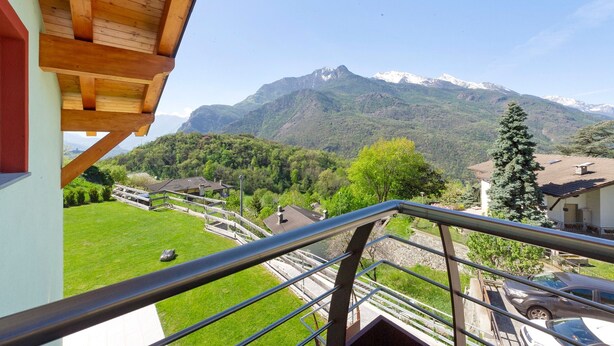 A balcony with a view of a mountain, a green lawn, and a parked car. - Suly Apartments 3 – Modern Accessible Stay with Mountain Views in Saint-Vincent (Cillian)