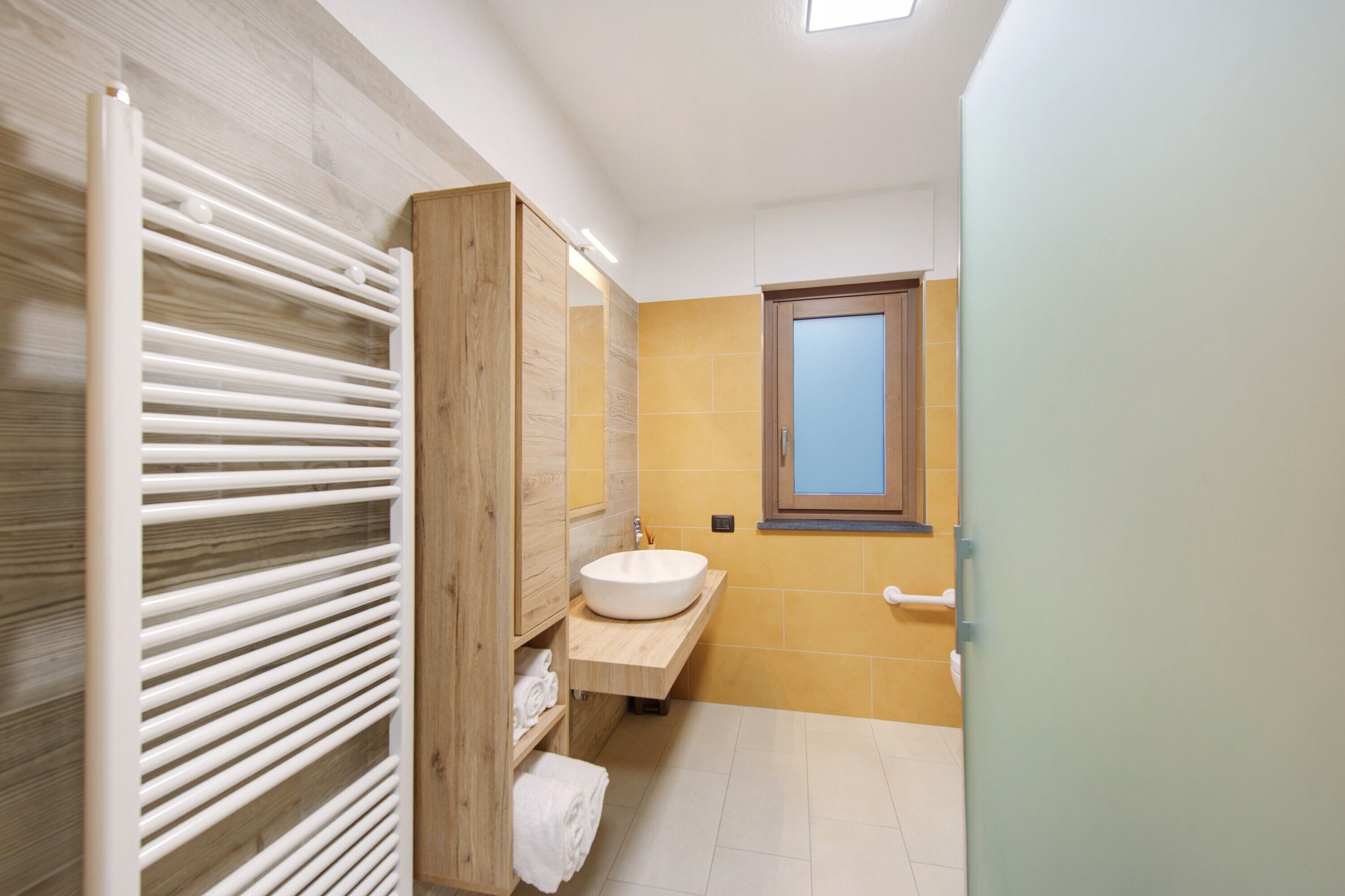 Un bagno con un mobile vanitario in legno, un lavandino bianco e un portasciugamani.