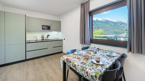 A modern kitchen with a dining area, a window with a mountain view, and a table set for two. - Suly Apartments 1 - cir0082 (Cillian)