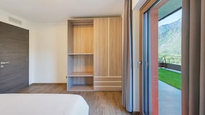 A modern bedroom with a bed, built-in wooden shelving, and a sliding glass door leading to a balcony with a mountain view. - Suly Apartments 1 - cir0082 (Cillian)