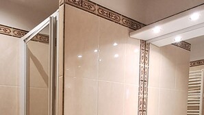 Ein Badezimmer mit Duschkabine aus Glas, Waschbecken mit Spiegel und gefliesten Wänden.