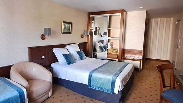 Ein Hotelzimmer mit Bett, Sessel, Schreibtisch und Kleiderschrank.