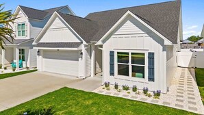 A residential house with a garage, a covered porch, and a well-maintained lawn. - Beach & Lake | Private Pool | Game Room | Near 30A (Panama City Beach)