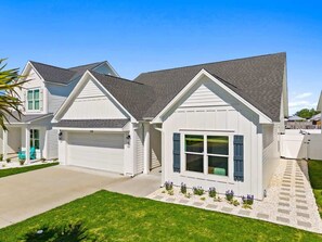 Ein Wohnhaus mit Garage, überdachter Veranda und gepflegtem Rasen.
