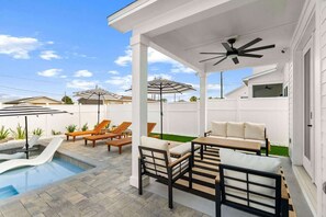 A covered outdoor patio with a pool, lounge chairs, and a table. - Beach & Lake | Private Pool | Game Room | Near 30A (Panama City Beach)
