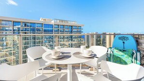 A rooftop terrace with a table set for two, overlooking a cityscape. - Luxury Sky Ala Moana Condo with Ocean & City Views (Honolulu)