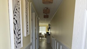 Um corredor com painéis decorativos na parede, piso de madeira com estrelas-do-mar e conchas, e um candelabro.