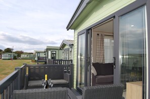 A modern outdoor seating area with wicker furniture and a glass door leading to a room.