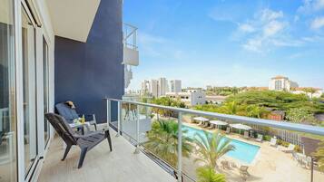 Ein Balkon mit Blick auf einen Pool und die umliegende Bepflanzung.