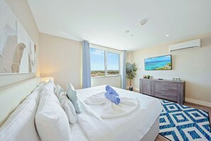 A hotel room with a large bed, a TV, a view of the sea, and a modern design. - Palm Beach Condo 3 Min. Walk 2 Beach & Restaurants (Noord)
