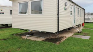 A single-story mobile home with a flat roof, two large windows, and a small porch area. - 63 St Andrews (Prestonpans)