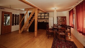 Una habitación amplia con una escalera de madera, un comedor con mesa y sillas, y una cocina con armarios y un refrigerador.