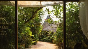 A garden pathway leading to a thatched-roof structure, surrounded by lush greenery and potted plants. - LIA Retreat Ba Na Hills (Da Nang)