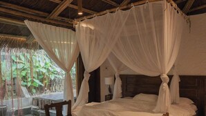 A room with a bed under a canopy, a wooden table, and a view of greenery outside. - LIA Retreat Ba Na Hills (Da Nang)