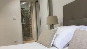 Ett hotellrum med en säng, en lampa och en synlig stenmur genom en öppen dörr.
