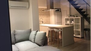 Ett modernt kök med en central köksö, en inbyggd ugn och en fläktkåpa i rostfritt stål.