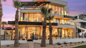 A modern multi-story house with large glass windows, a balcony, and a slide. - The Oasis Utah: Lagoon-Front, Pool, Slide, Theater (St. George)