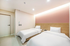 A hotel room with two single beds, a wooden headboard, a bedside table with a phone, and a door with a handle. - Jeonju J-Brown Hotel (Jeonju)