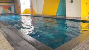 En inomhuspool med kakel runt kanten och en väggdekoration med färgstarka motiv.