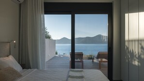 Un dormitorio con una cama grande, vistas al mar y una terraza de madera exterior.