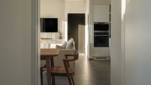 Una cocina moderna con armarios blancos, horno empotrado y televisor de pantalla plana sobre la encimera.