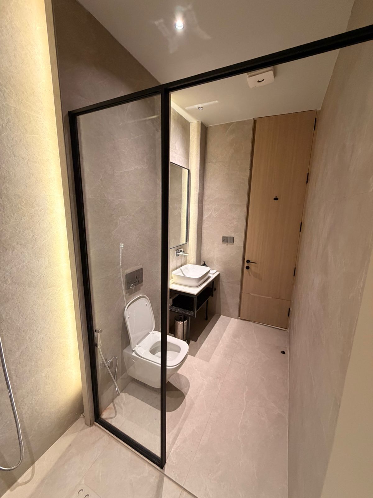 Un baño moderno con mampara de vidrio, inodoro, lavabo y zona de ducha.