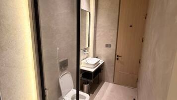 Un baño moderno con mampara de vidrio, inodoro, lavabo y zona de ducha.