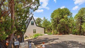 A single-story house with a gabled roof, surrounded by trees and a paved driveway. - Luxe Forest A-Frame Escape w/ Deck & Fire-Pit (Heber-Overgaard)