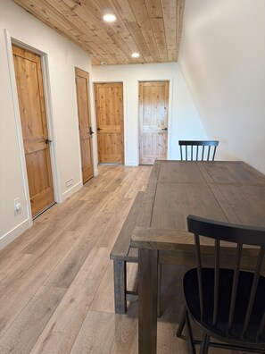 A spacious room with a wooden floor, a large table, and three wooden doors.