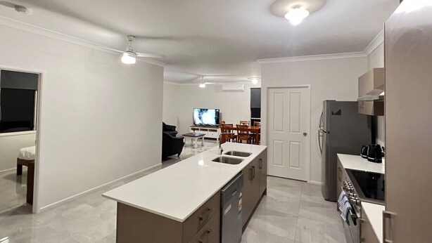 Een moderne keuken met een centraal eiland, inbouwapparatuur en een eethoek met een televisie.