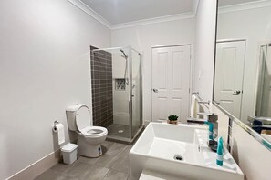 Et moderne badeværelse med toilet, bruser og vask.