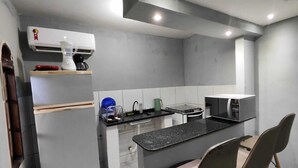 A compact kitchen with a refrigerator, microwave, and sink. - Complete Studio 2 (Rio das Ostras)