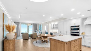 Una cucina moderna con mobili bianchi, una grande isola e elettrodomestici in acciaio inossidabile.